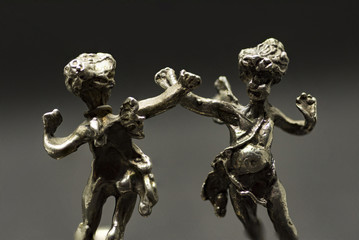 two metallic figurine angels are dancing