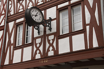 Fototapeta na wymiar Ventanas y reloj en fachada de casa antigua típica en Alemania.