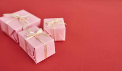 Tiny pink gift boxes over red background. Valentones day background