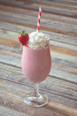 Delicious strawberry smoothie on wooden background