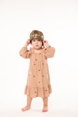 Cute little girl in beige dress with gold crown isolated on white background. Portrait of happy little girl.