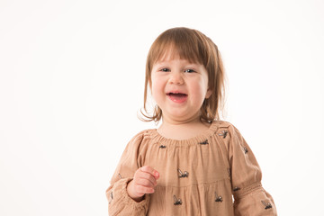 Cute little girl in beige dress isolated on white background. Portrait of happy little girl on white background. Sweet girl with curly hair.