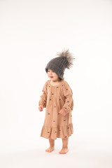 Portrait of happy little girl. Cute little girl in beige dress in a gray hat isolated on white background.
