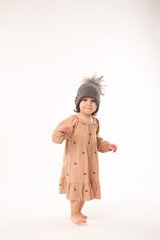 Portrait of happy little girl. Cute little girl in beige dress in a gray hat isolated on white background.