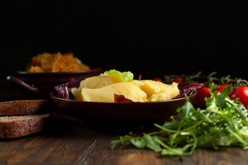 mashed potatoes, bread, greens and cherry tomatoes on a dark wooden table