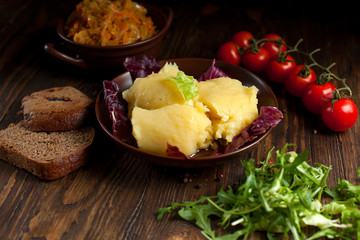 mashed potatoes, bread, greens and cherry tomatoes on a dark wooden table