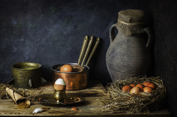 Classic still life with chicken eggs place in nest with old jar,copper pots and herbs on rustic wooden background © dinasaeed