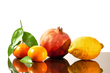 Beautiful fruits citrus family, clementines, tangerine, pomegranate and lemon on white shine background