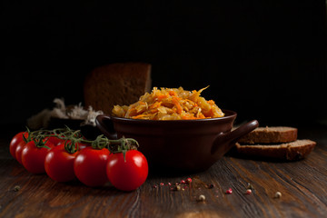 stewed cabbage, bread and cherry tomatoes on a dark wooden table