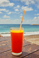 Orange cocktail on wooden table. Sunny day near mediterranean sea.