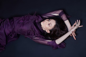 Contrast fashion Armenian woman portrait with big blue eyes lying on the floor in a purple dress....