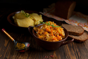 stewed cabbage, bread and cherry tomatoes on a dark wooden table