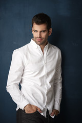 Handsome young man studio portrait. Studio portrait of confident young businessman wearing shirt and looking at camera whle standing at dark background with copy space.