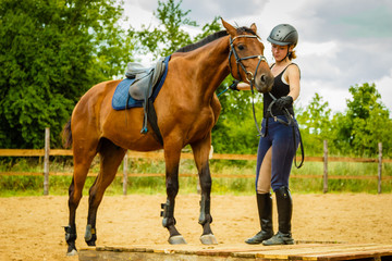Obraz premium Jockey young woman getting horse ready for ride