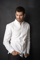 Obraz premium Thinking young businessman portrait. Studio portrait of handsome man wearing shirt while sitting at dark background and looking at camera