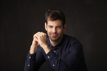 Handsome young man studio portrait. Studio portrait of confident young businessman wearing shirt and looking at camera whle standing at dark background with copy space.