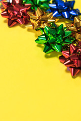 Close up view of colorful shiny paper gift or present bows on bright yellow background with copy space