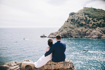 wedding couple, newlyweds sitting with their backs with a beautiful view of the mountains and the sea - 190943354