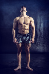 Good Looking Young Gym Fit Man Showing His Sexy Six Pack Abs While Looking Up, on Dark Background.