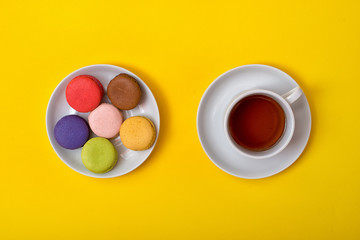 Colorful sweet macaroons and a cup of tea. Delicious breakfast. Top view.