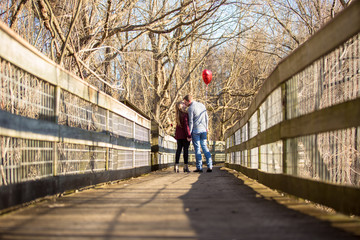 Attractive young caucasian couple walking in the park. Dating, Valentine balloon and red rose.