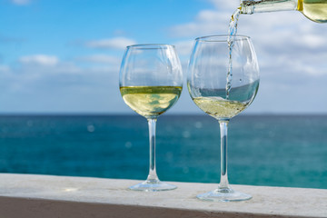 Waiter pouring glass of white wine on outdoor terrace with sea view