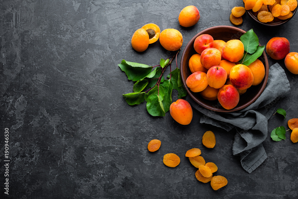 Wall mural fresh apricots with leaves and dried in bowl on table