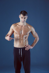 Fototapeta premium muscular man. Muscular man on a grey background showing muscles. Fitness instructor. Fitness professional. Workout. Men's fitness.