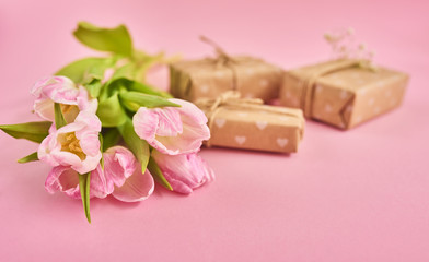 Fototapeta na wymiar Valentines day background with pink tulips and gift box over pink background. Space for text