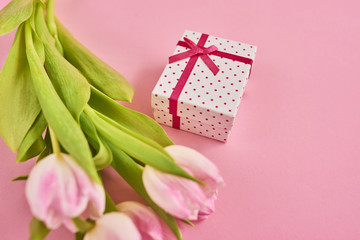 Valentines day background with pink tulips and gift box over pink background. Space for text