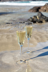 Two glasses of champain or cava sparkling wine served on the white sandy tropical beach, luxury resort with sea view, romantic vacation