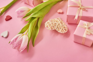 Valentines Day background with pink tulips, red ribbon and gift box over pink background. Space for text