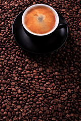 Black coffee cup and saucer one single for espresso or capuccino filled full of coffee beans on a background of scattered dark coffee beans photo 