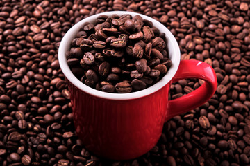 Red coffee cup mug one single for espresso or capuccino filled full of coffee beans on a background of scattered dark coffee beans photo 