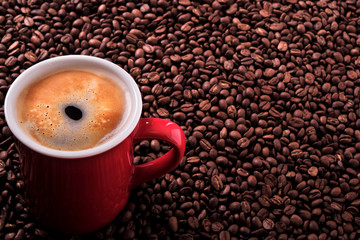 Red coffee cup mug one single for espresso or capuccino filled full on a background of scattered dark coffee beans photo 