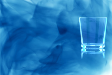 Empty glass of whiskey enveloped in blue smoke.