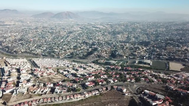erial footage of a residential area in Tijuana, Baja California, Mexico during a Santana, local name for sand storm. High density of houses in a desert area, dusty sky.