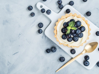 Vanilla tartlets with blueberry berries on light background.