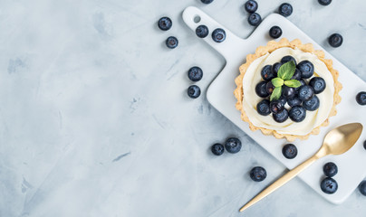 Vanilla tartlets with blueberry berries on light background.