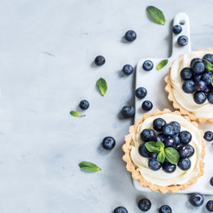 Vanilla tartlets with blueberry berries on light background.