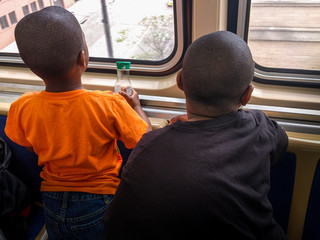 Two black boys looking out of the window on an elevated train.