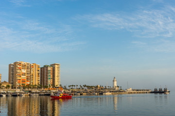 White lighthouse and the tall buildings of Malaga with their reflections in Malaga, Spain, Europe