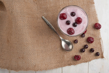 Fototapeta na wymiar yogurt in a glass with berries on sacking and texture