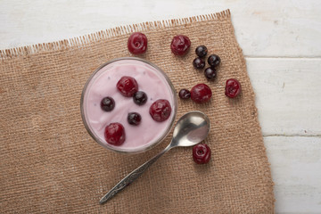 yogurt in a glass with berries on sacking and texture