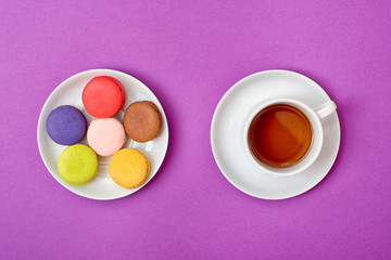 Colorful sweet macaroons and a cup of tea. Delicious breakfast. Top view.