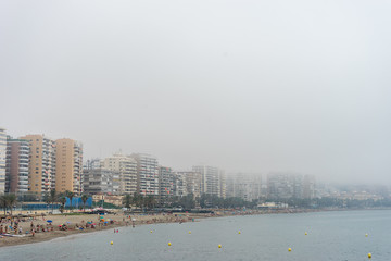 Obraz premium The building along the coastline at Malagueta beach covered by fog in Malaga, Spain, Europe
