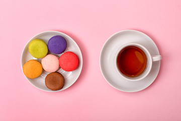  Colorful sweet macaroons and a cup of tea. Delicious breakfast. Top view.