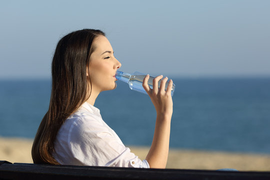 Woman drinking water from a bottle on the beach