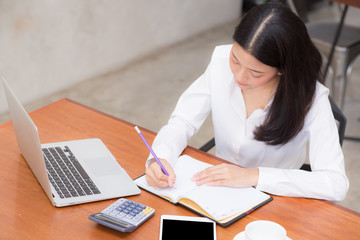 Business asian woman writing on notebook on table with laptop, girl work at coffee shop, freelance business concept.