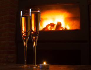 Two glasses of red wine in front of log fire